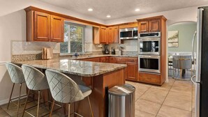 A kitchen with wooden cabinets, a granite countertop, and stainless steel appliances. - BNEW 6BR Postmodern 3k+sqft. Home in ABQ w/ Pool! (Albuquerque)