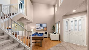 A spacious living area with a pool table, a staircase, and a door with decorative glass panels. - BNEW 6BR Postmodern 3k+sqft. Home in ABQ w/ Pool! (Albuquerque)