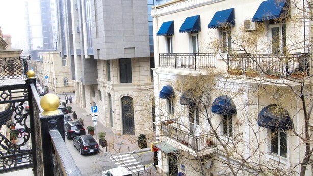A multi-story building with balconies, a street view, and parked cars. - Pilot Inn Hotel Baku (Baku)