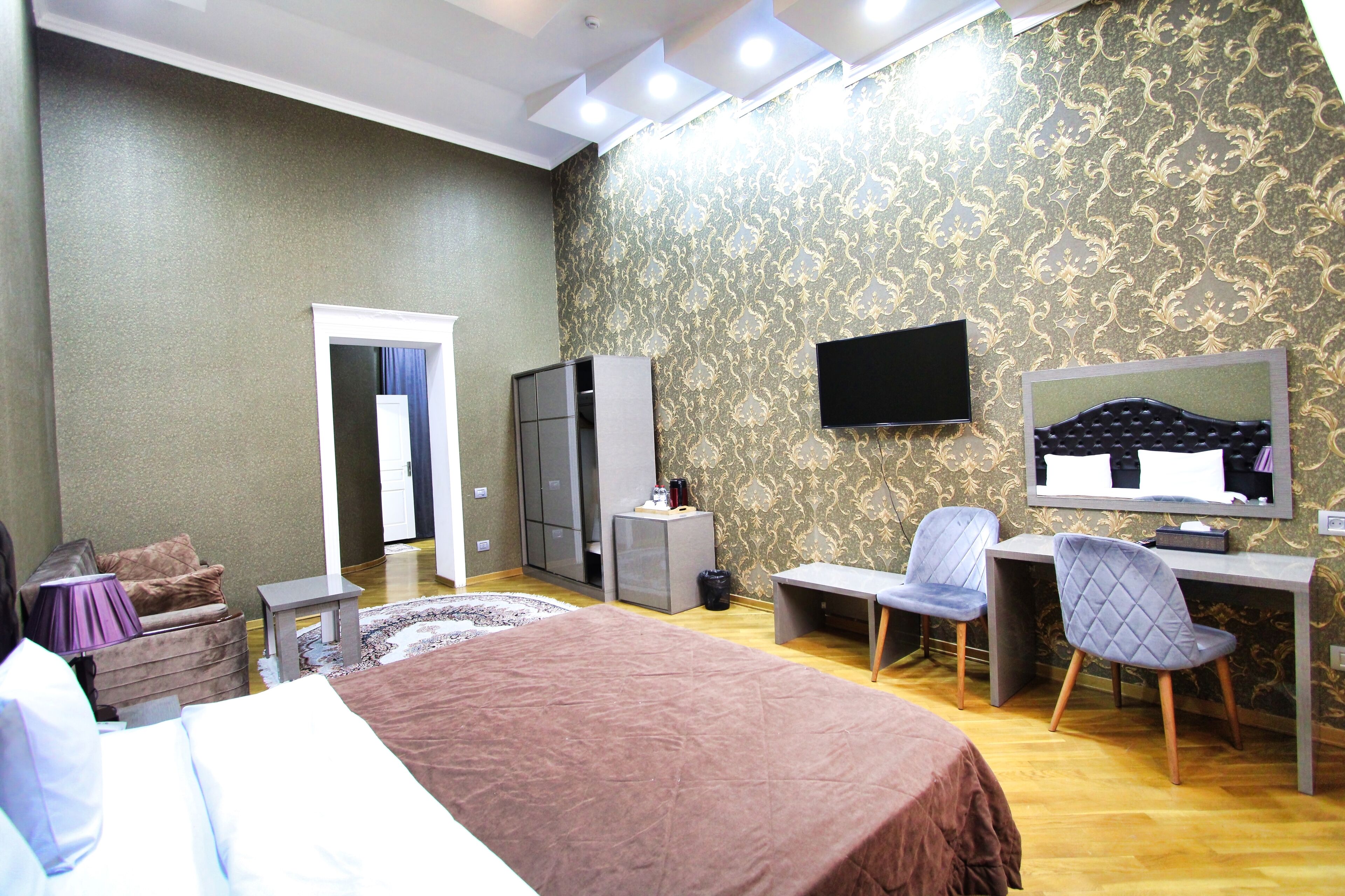 Een hotelkamer met een bed, een bureau met stoel, een televisie en een kledingkast.