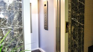 An elevator with a marble wall and a door with a textured pattern. - Pilot Inn Hotel Baku (Baku)
