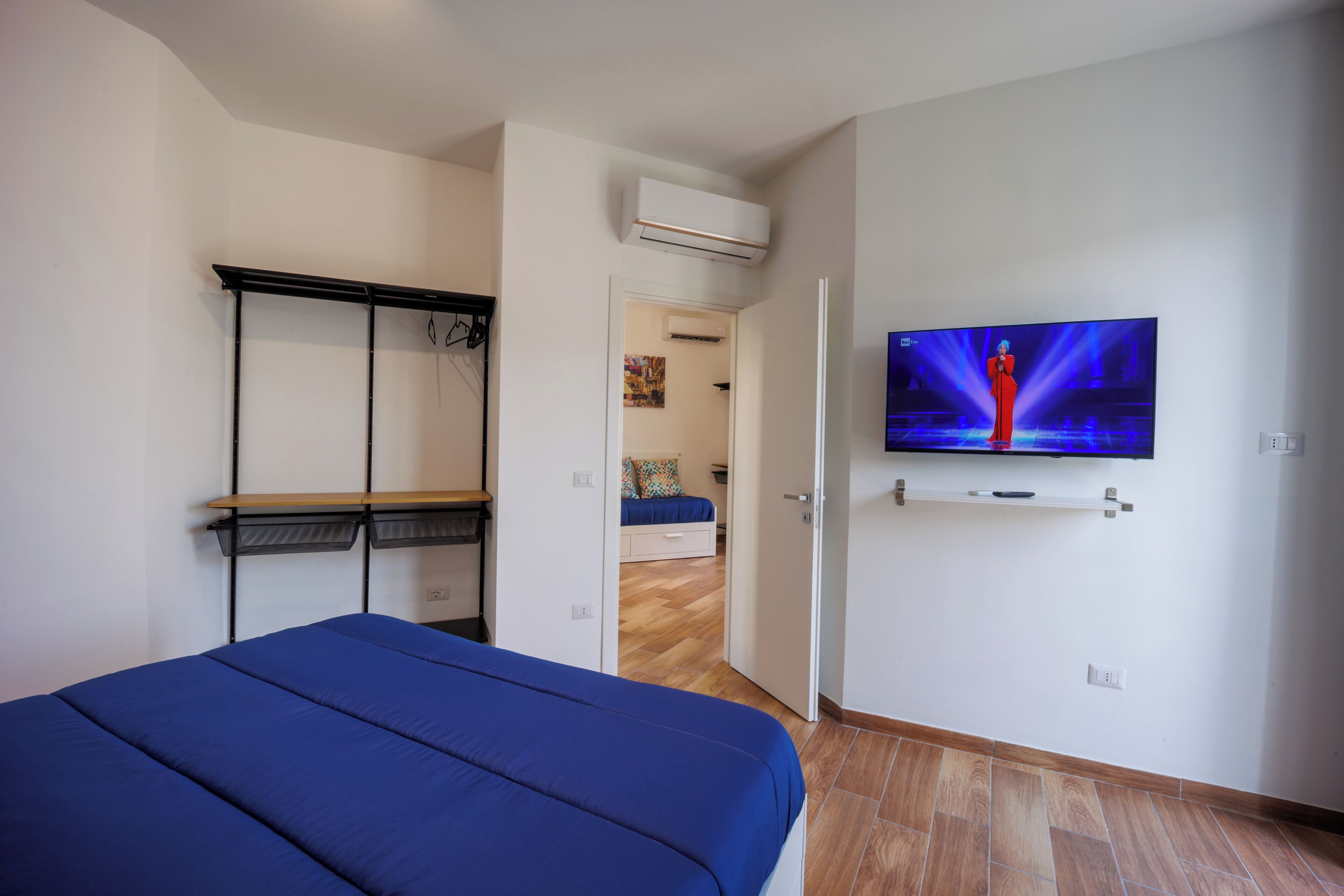 A bedroom with a bed, a TV mounted on the wall, and a wardrobe.