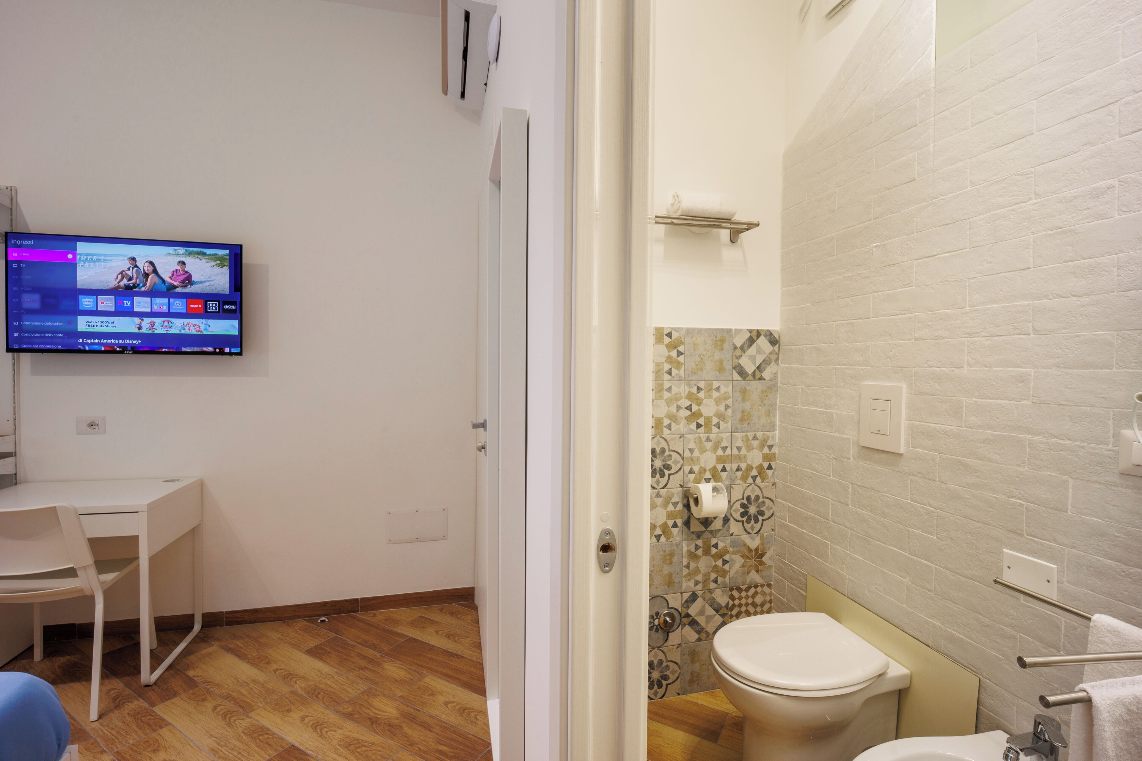 Een badkamer met toilet, wastafel en een tv aan de muur die een sportzender toont.