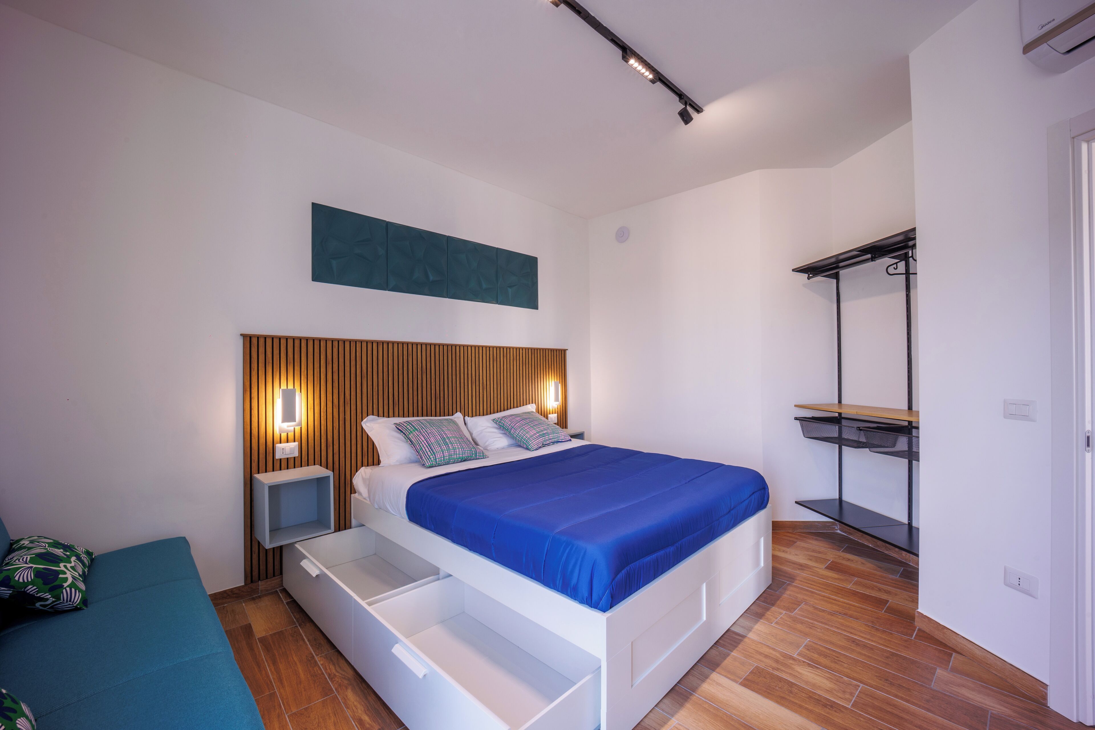 Un dormitorio moderno con cama, mesitas de noche, un banco empotrado y un armario.