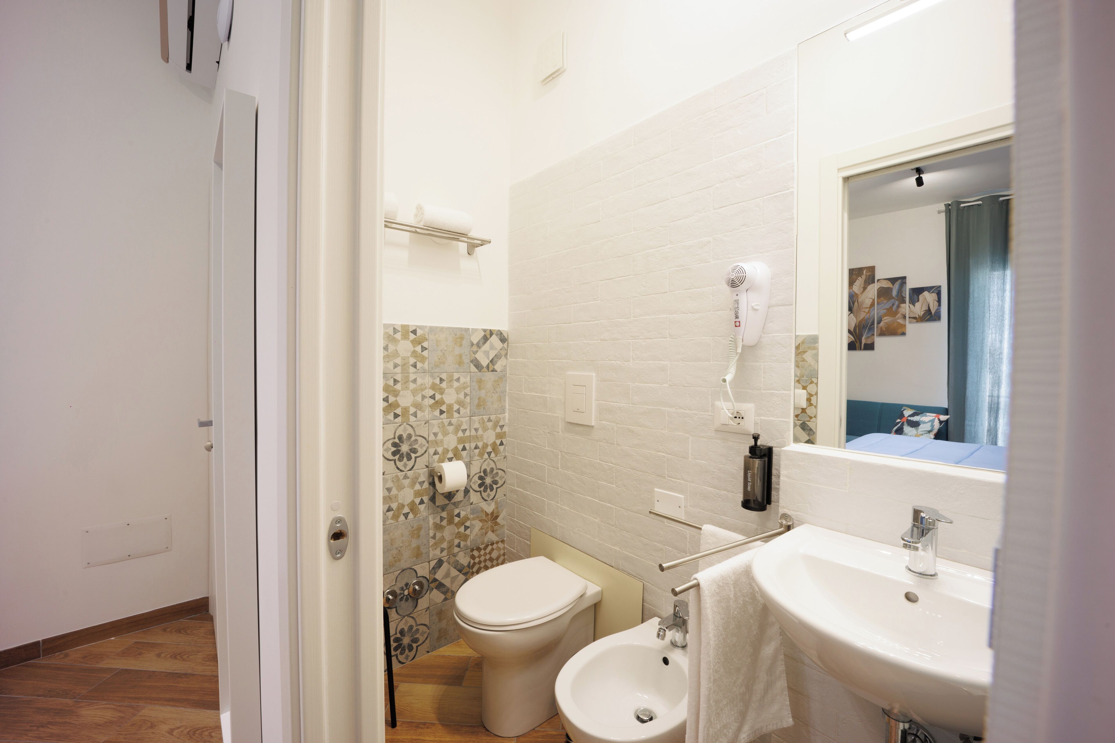 A bathroom with a toilet, bidet, sink, and mirror.