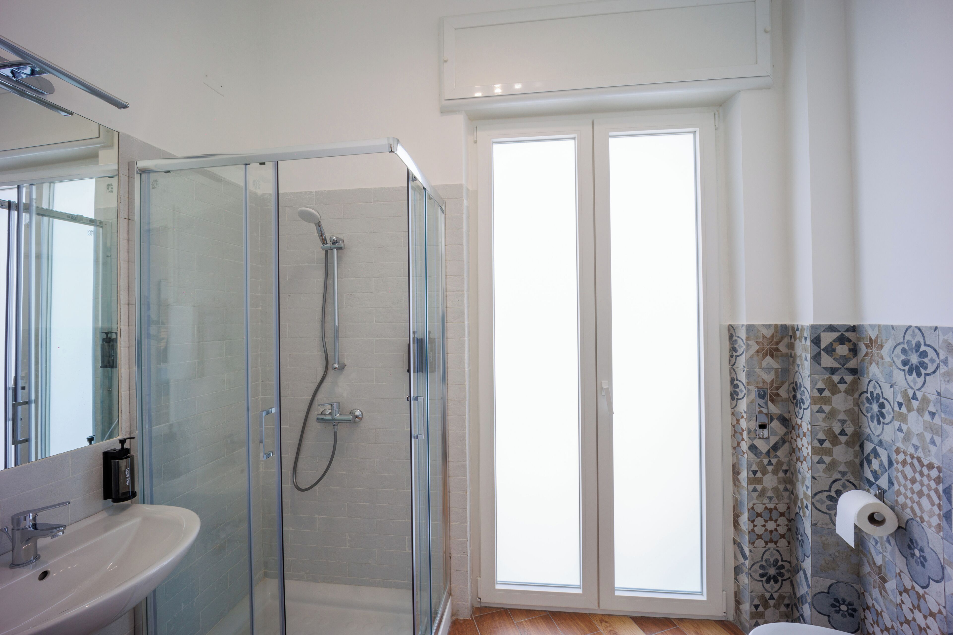 A bathroom with a glass shower enclosure, a sink, and a toilet.