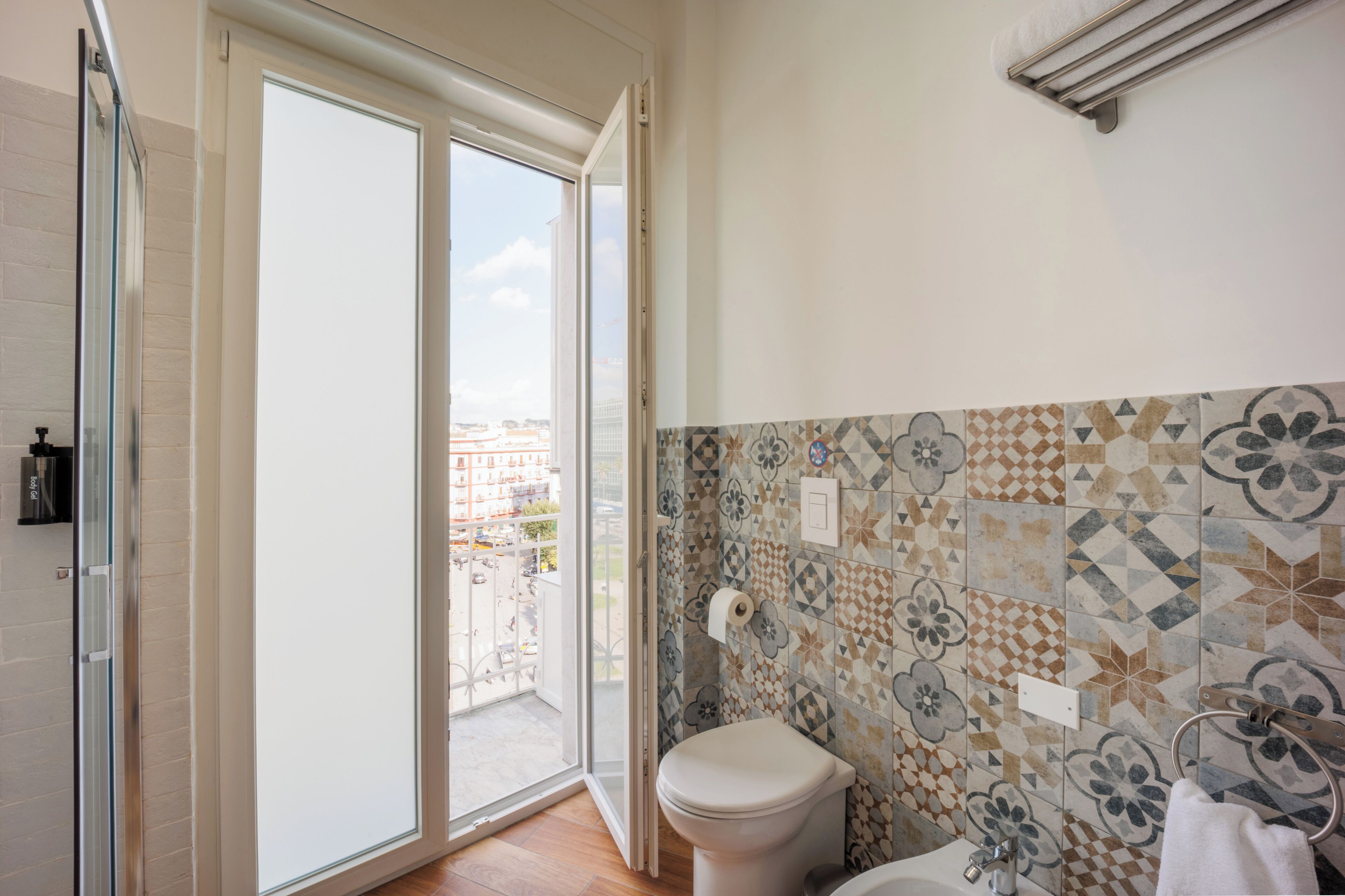 A bathroom with a toilet, a shower, and a glass door leading to a balcony.