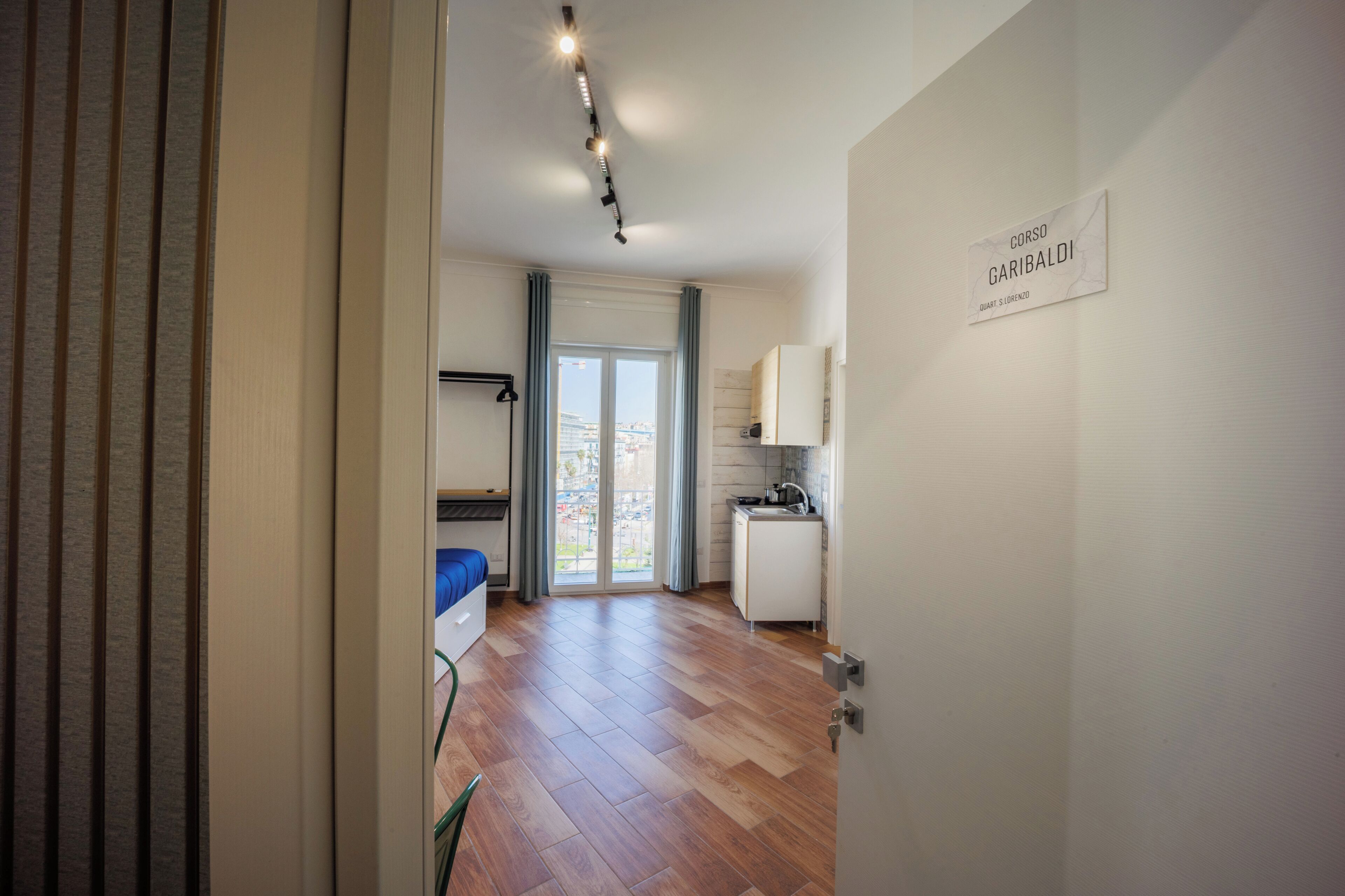 A modern apartment with a kitchenette, a dining area, and a large sliding glass door leading to a balcony.