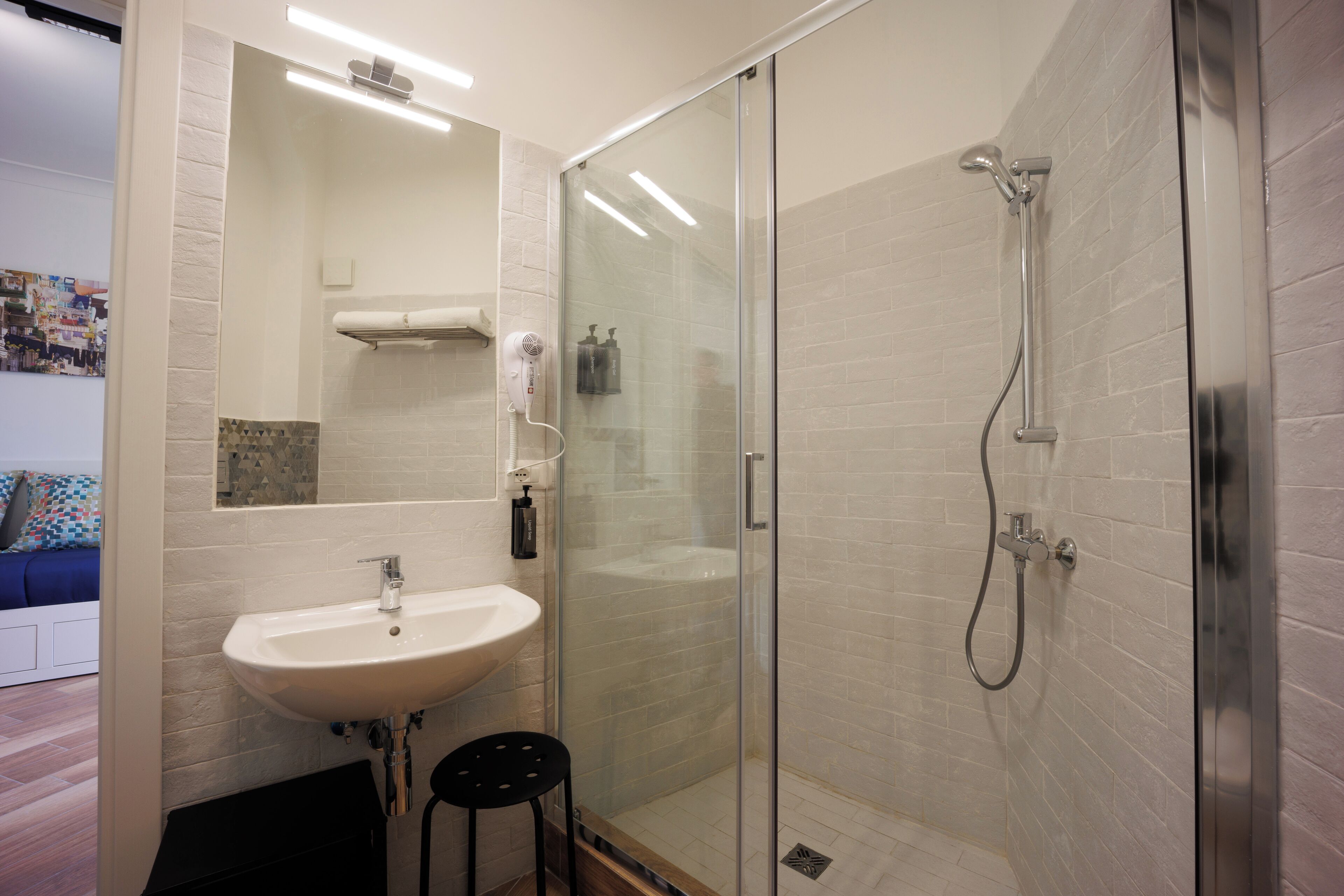 Une salle de bain moderne avec une douche à parois de verre, un lavabo blanc et un sèche-cheveux.