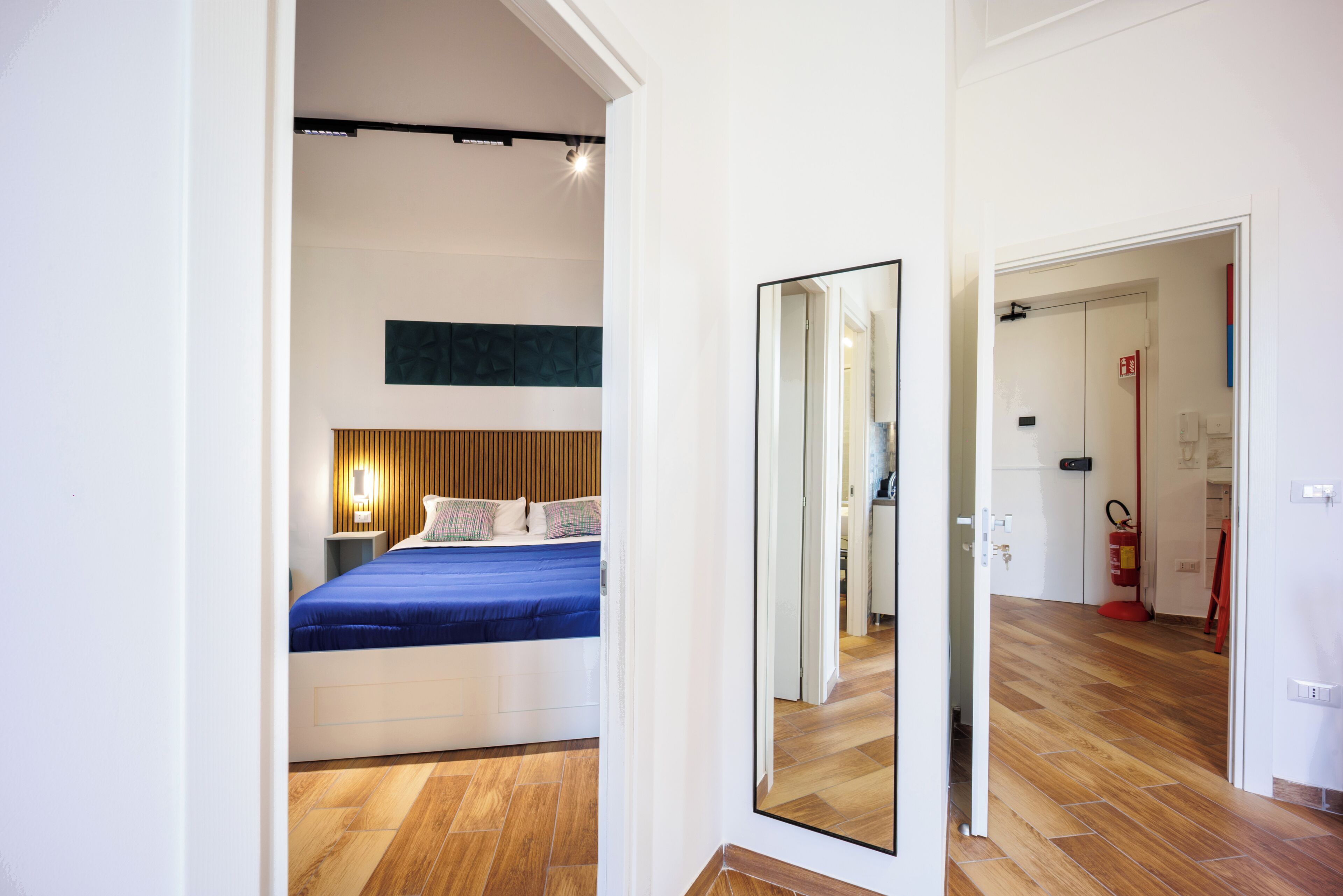 A modern hotel room with a large bed, a mirror, and a wooden floor.