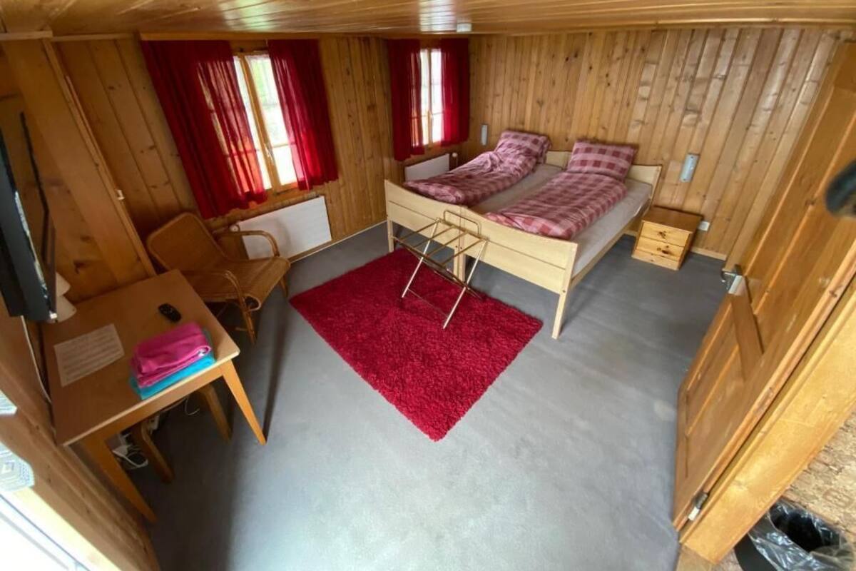 A small wooden cabin with a bunk bed, a desk, and a red rug.