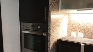 A kitchen with a built-in oven, microwave, and granite countertop.