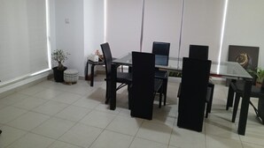 A conference room with a glass table, black chairs, a laptop, and a potted plant.