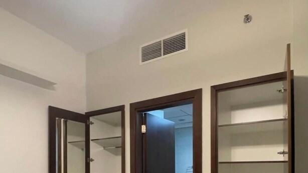A room with a large wardrobe, a mirror, and a door leading to another room.