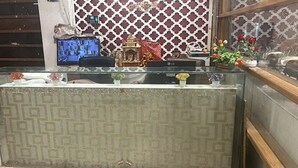 Uma receção com um tapete estampado, uma televisão e objetos decorativos, incluindo flores e figuras.