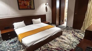 Quarto de hotel com uma cama grande, mesa de cabeceira, escrivaninha e uma cadeira.