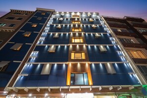 A multi-story hotel with a modern facade, featuring a grid of windows and illuminated panels. - FabHotel I Residency - Koramangala Nr. St. John's Hospital (Bengaluru)