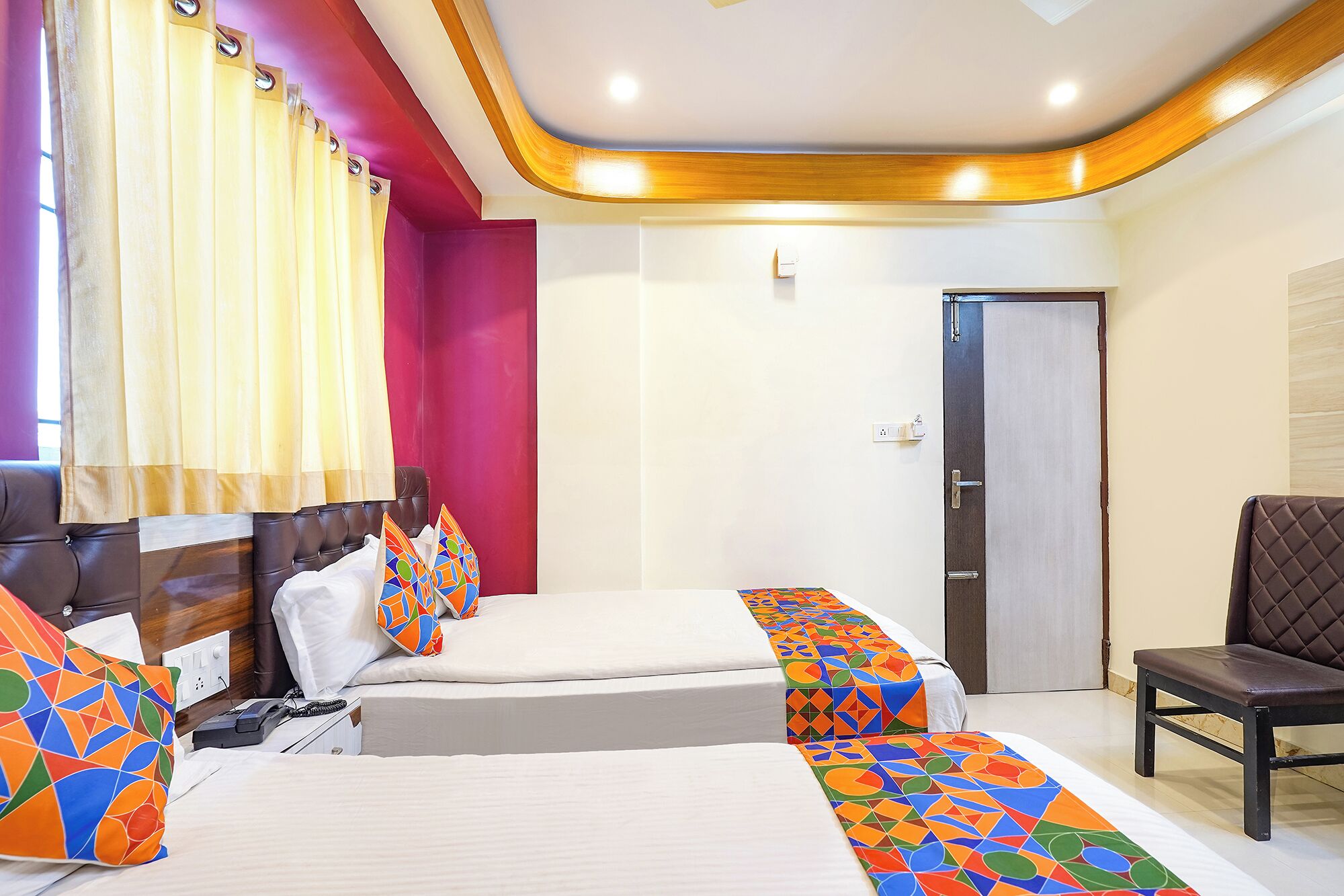 A hotel room with two beds, a chair, and a door.
