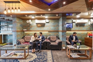 A lobby with leather sofas, a glass coffee table, and a television on the wall.