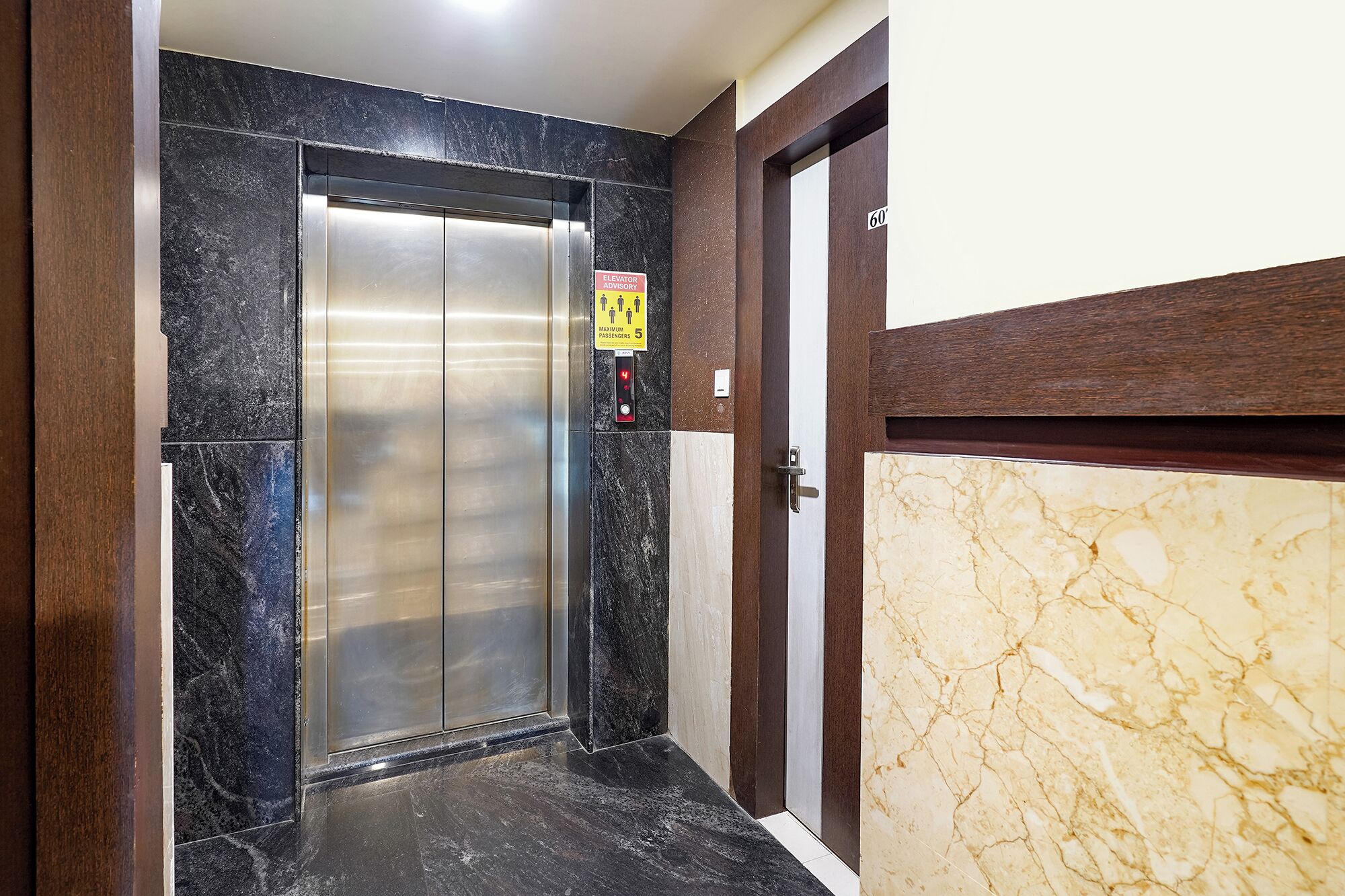 An elevator with a maximum capacity sign of 5 passengers, a door with a number 60, and a marble floor.