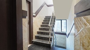 A staircase with marble steps and metal railings, leading to a landing with a door and a window. - FabHotel I Residency - Koramangala (Nr St. John's Hospital) (Bengaluru)