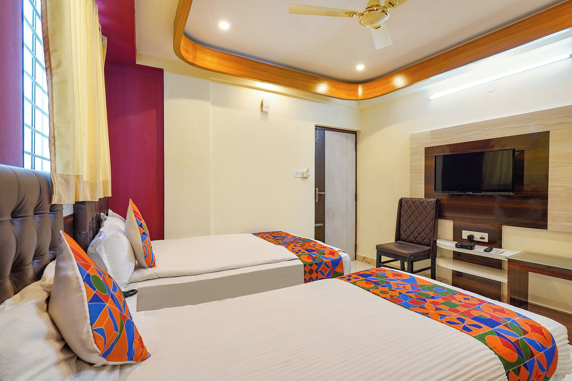 A hotel room with two beds, a TV, a desk, and a chair.