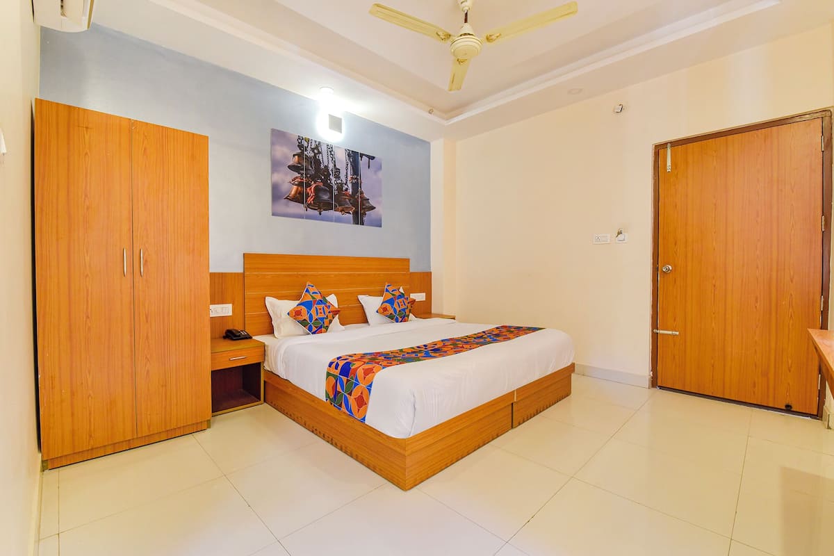 A bedroom with a wooden bed, a nightstand, a wardrobe, and a ceiling fan.