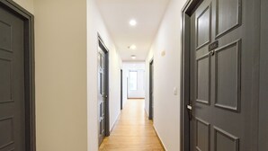 A hallway with dark wooden doors, light-colored walls, and a wooden floor. - Fabhotel White Ridge (Hyderabad)