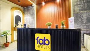 A reception desk with a 'fab hotels' sign, wooden paneling, and potted plants. - Fabhotel White Ridge (Hyderabad)