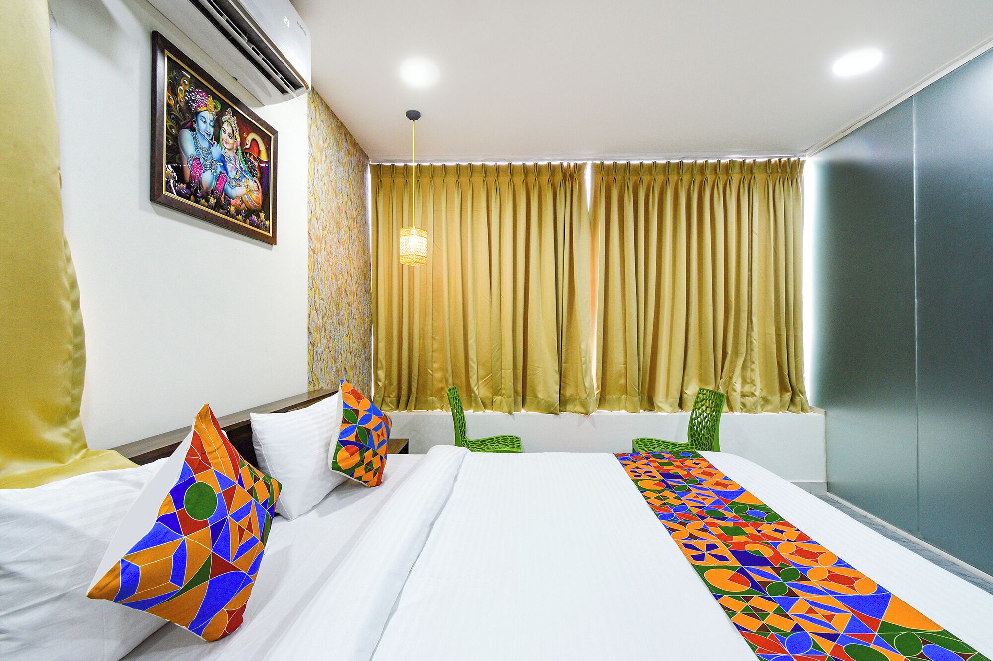 Una habitación de hotel con una cama, almohadas, una ventana con cortinas y un aire acondicionado instalado en la pared.