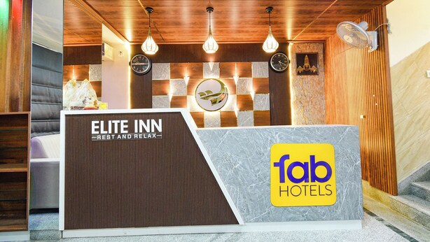 Un comptoir d’accueil avec un panneau décoratif en bois, une horloge et le logo de « fab hotels ».