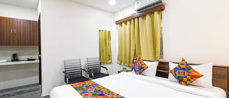 A hotel room with a bed, a desk, a chair, a ceiling fan, and an air conditioning unit.