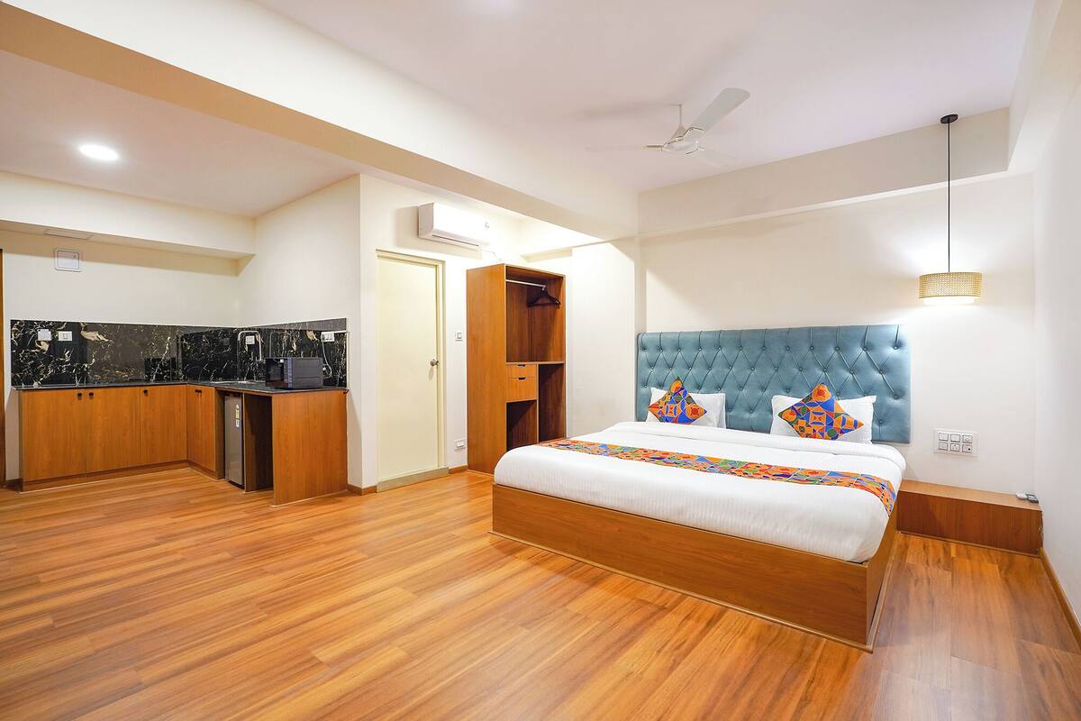 Habitación de hotel con cama, armario de madera, kitchenette y ventilador de techo.