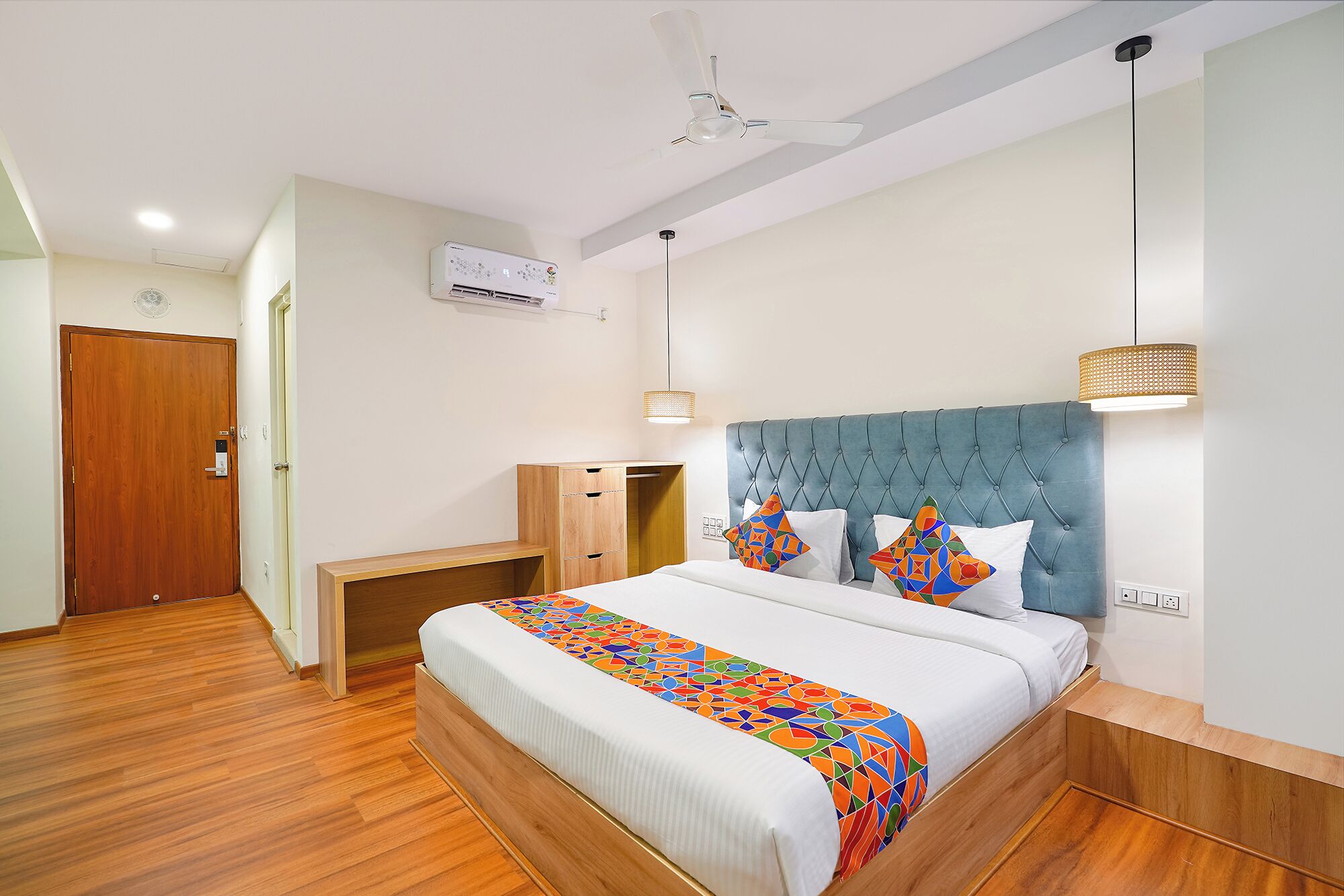 Une chambre d’hôtel équipée d’un lit, d’un bureau, d’une armoire et d’un ventilateur de plafond.