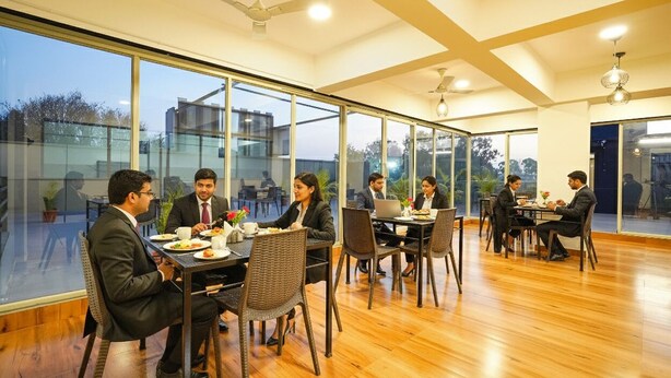 Un'area pranzo moderna con ampie finestre, pavimento in legno e ventilatori a soffitto.