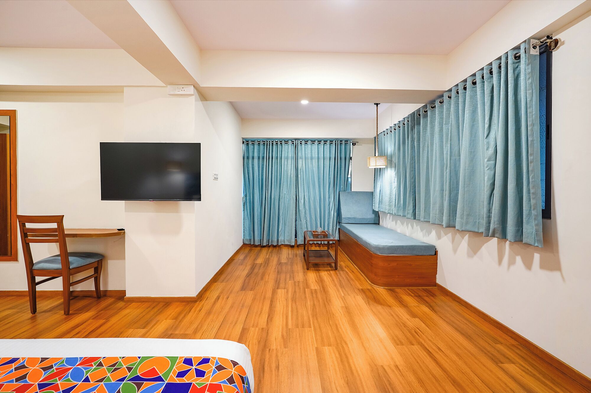 A room with a bed, a desk, a chair, a TV, and a sofa.