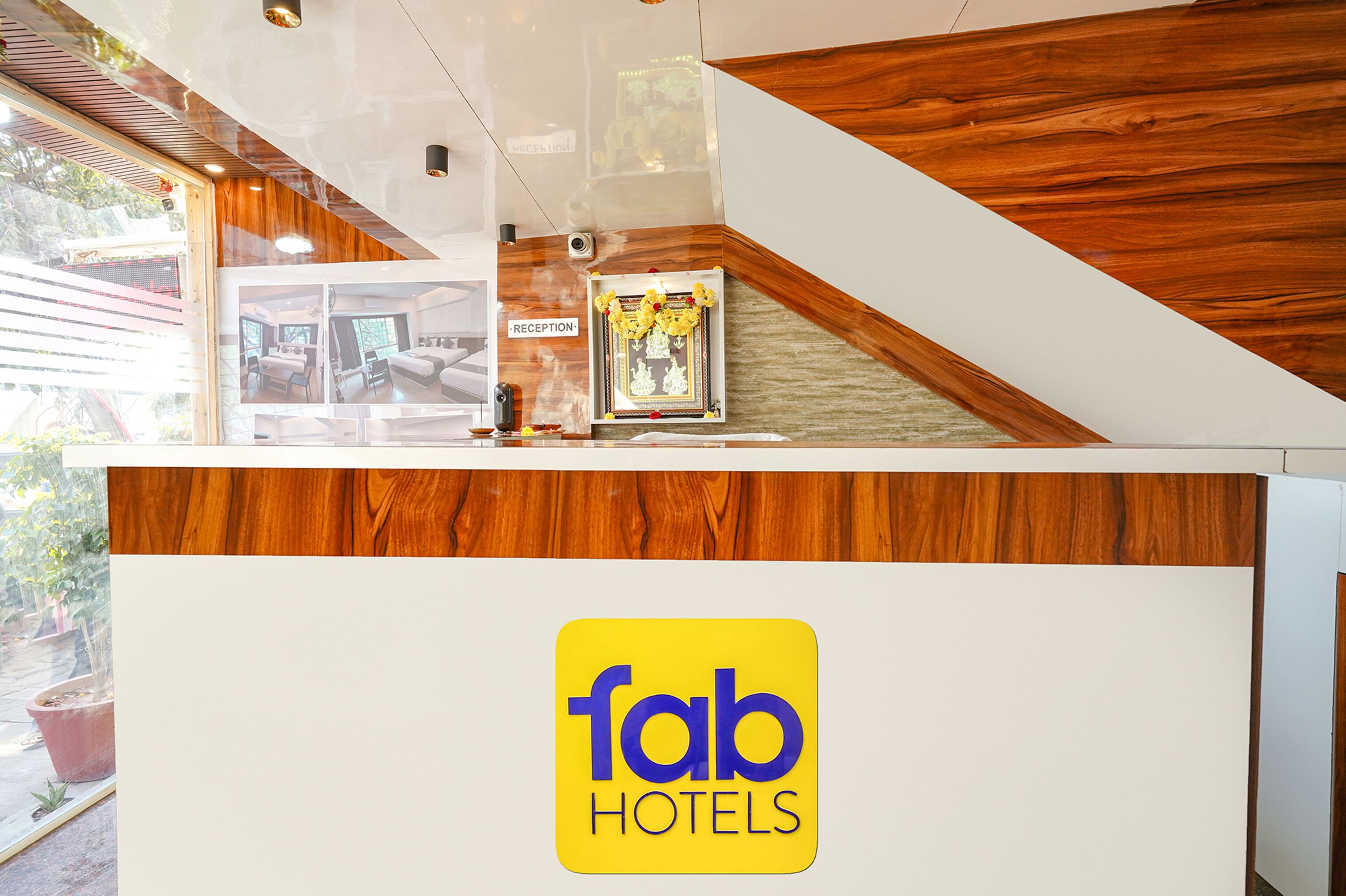 Una reception con il cartello 'fab hotels', un'area ricevimento e un quadro di una camera.