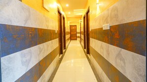 A hallway with marble walls, wooden doors, and recessed lighting. - FabHotel Royal N Comforts (Bengaluru)