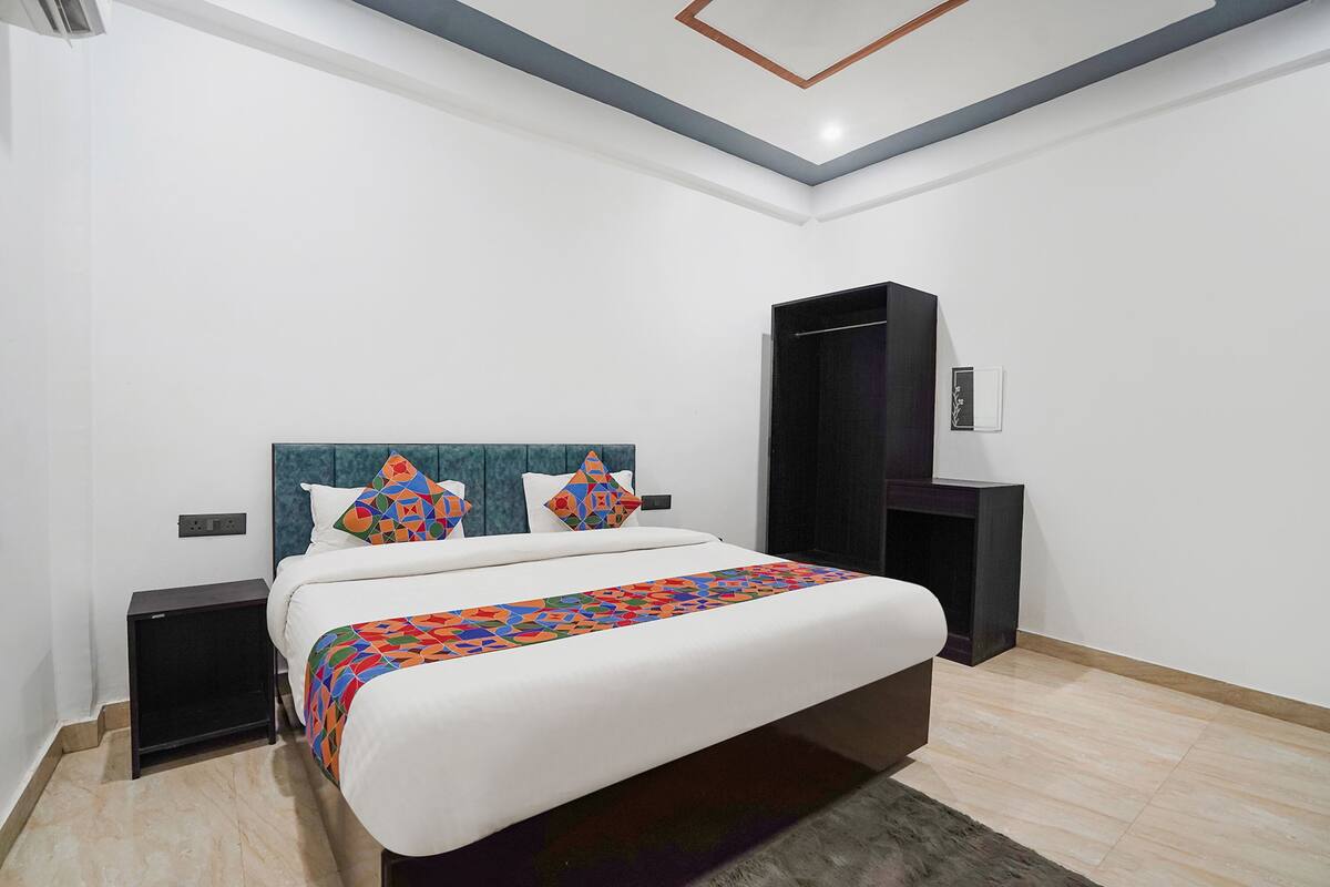 A modern bedroom with a large bed, a headboard, a bedside table, and a wardrobe.