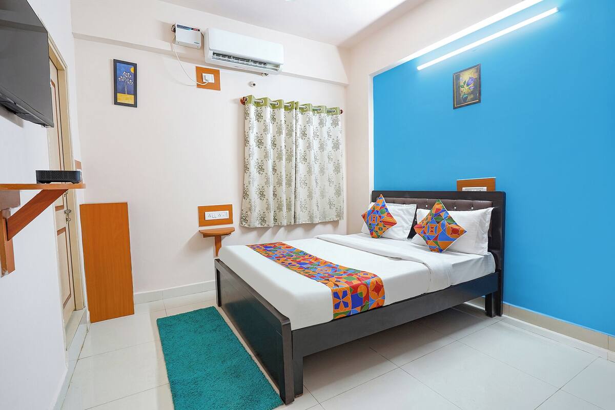 Een slaapkamer met een bed, een televisie, een airconditioner en een blauwe wand.