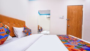 Une chambre d’hôtel avec un lit, une porte en bois et un miroir au mur.
