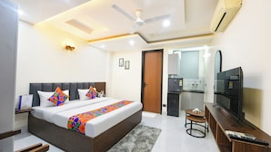 A modern hotel room with a large bed, a TV, a desk, and a bathroom visible through an open door. - FabHotel RR Premium (Gurugram)