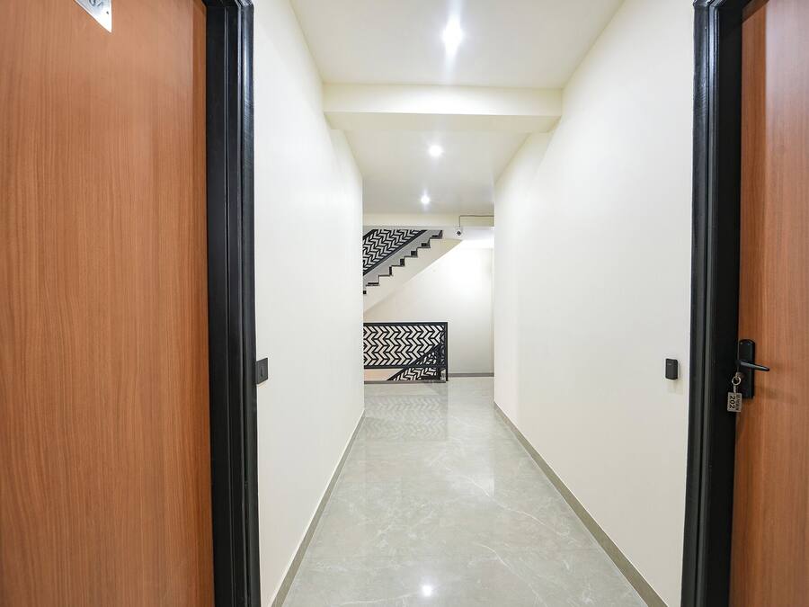 A hallway with a marble floor leading to a staircase with a black and white patterned railing.