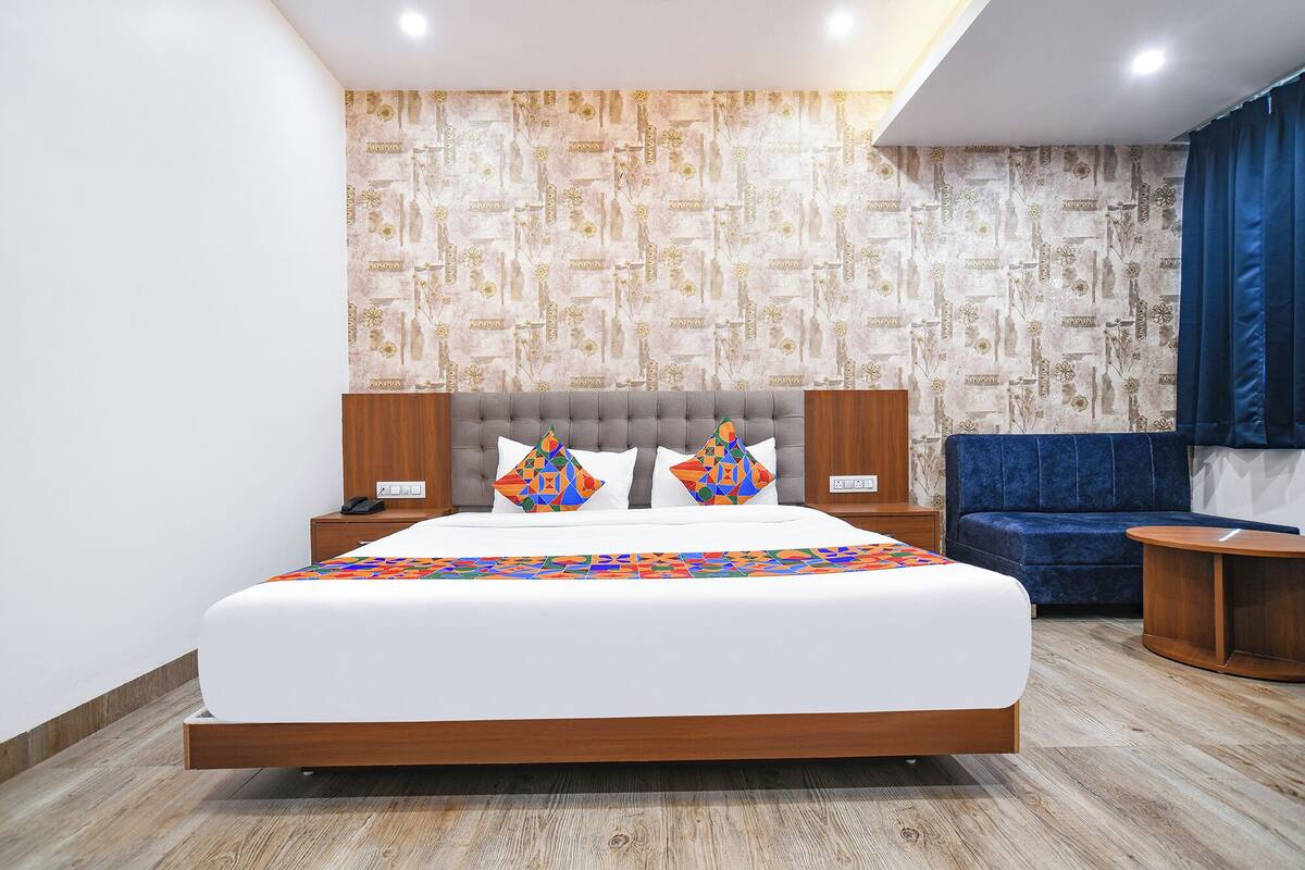 Moderni hotellihuone, jossa on suuri sänky, sohva ja pieni pöytä.