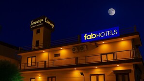 A building with a sign for 'Fab Hotels' and 'Lennaaga Hotel by LEBNOTTIA' at night, featuring multiple balconies and windows. - Fabhotel Jayaditya Palace (Ayodhya)