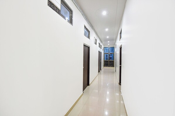 A long, narrow hallway with white walls and a shiny tiled floor.