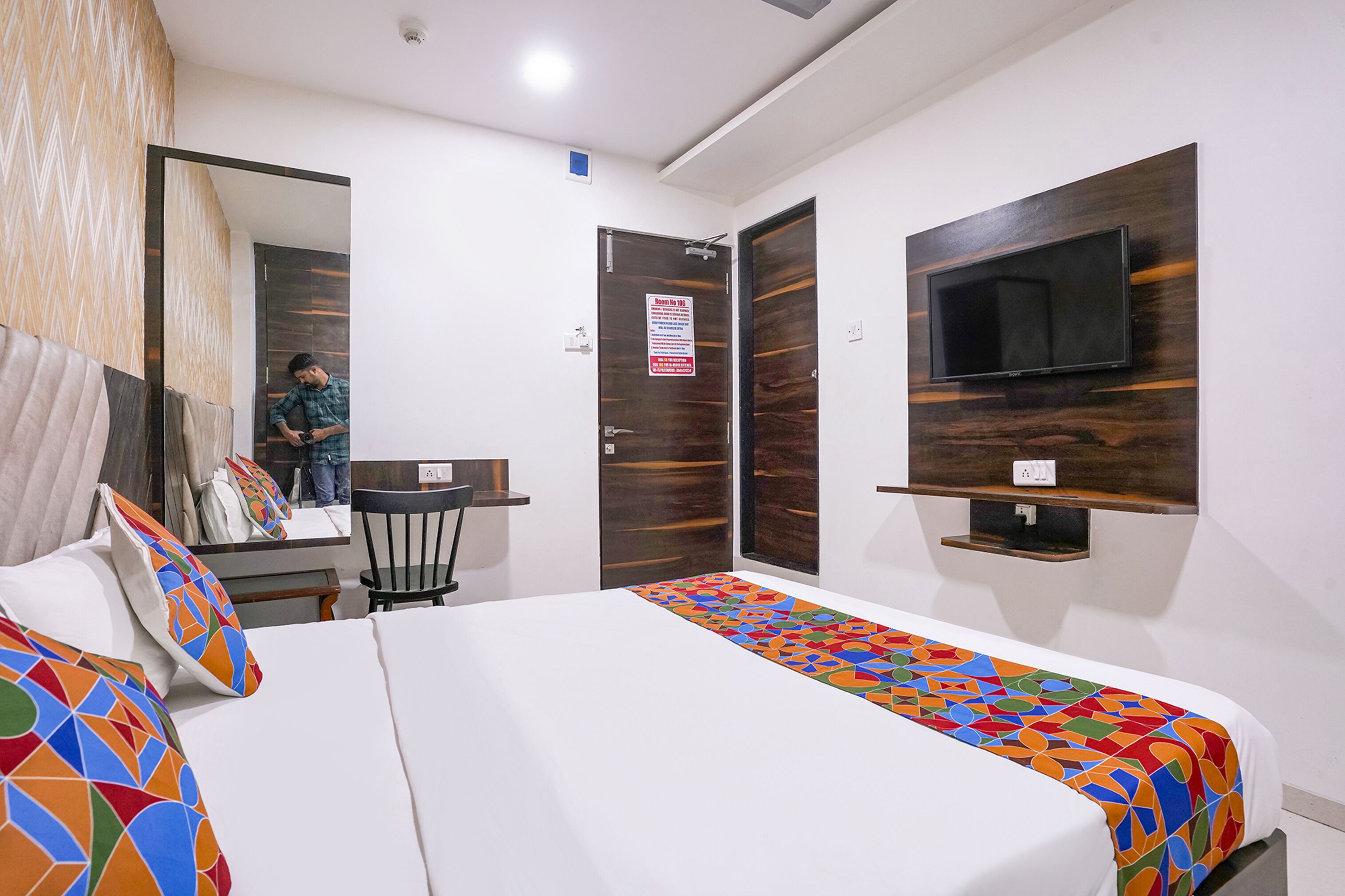 Une chambre d’hôtel avec un lit, un téléviseur fixé au mur, un bureau et une chaise.