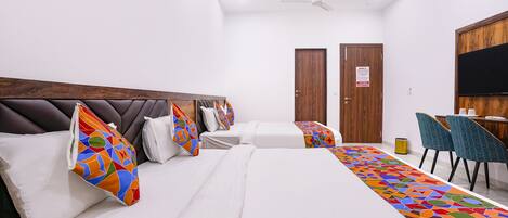 Habitación de hotel con dos camas, cabecero de madera, una alfombra decorativa de colores y un escritorio con sillas.