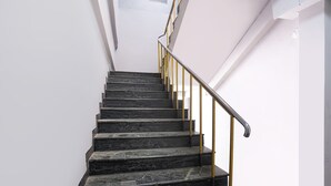 Una escalera con escalones de mármol negro y barandilla amarilla.