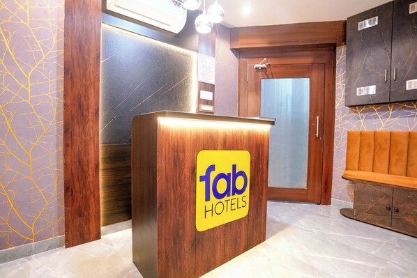 A reception desk with a 'fab hotels' sign, wooden paneling, a door, and a bench.